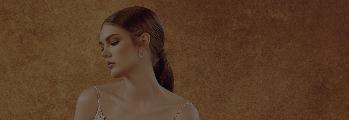 Bride in a lace wedding dress with a deep V-neck against a wall.