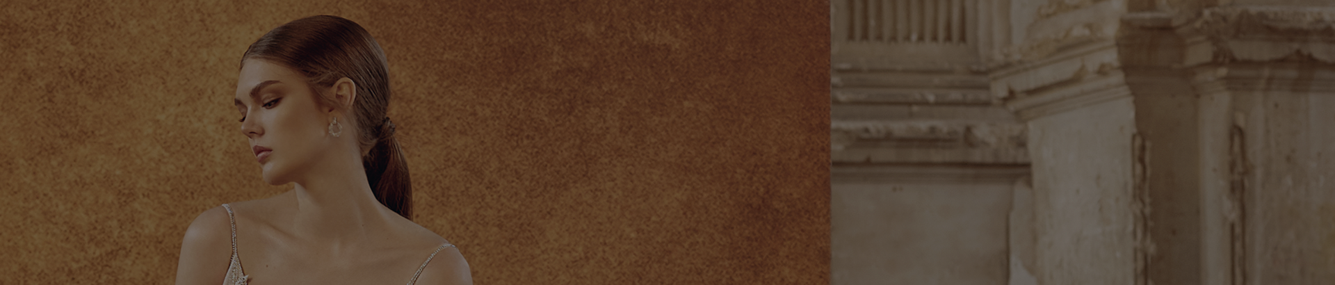 Bride in a lace wedding dress with a deep V-neck against a wall.