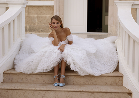 Bride in wedding dress sitting on steps in front of house